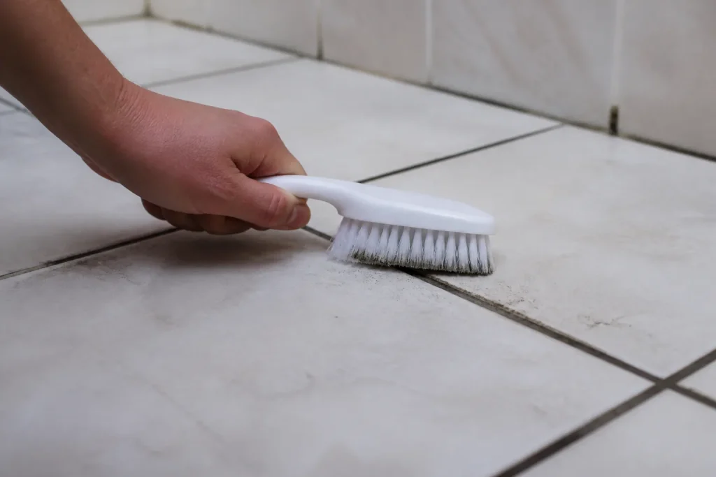 Brosse blanche frottant un joint de carrelage noirci