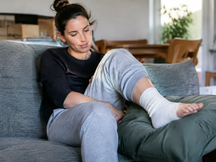 Femme assise, cheville bandée posée sur un coussin