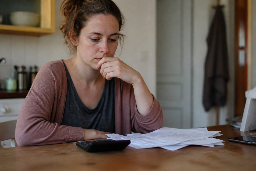Femme pensive devant une calculatrice et des documents