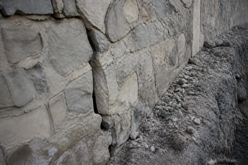 Mur de pierre fissure pres dune tranchee avec gravier