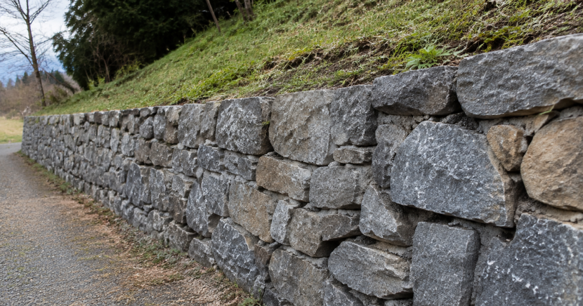 Mur de pierre grise retenant un talus en pente
