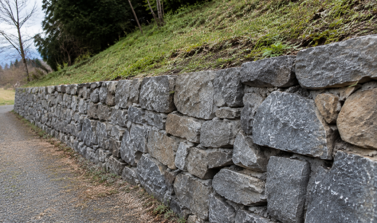 Mur de pierre grise retenant un talus en pente