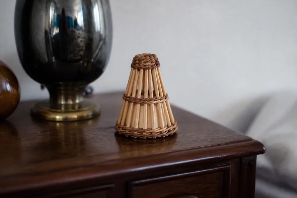 Petit cone aux lattes claires pose sur une commode