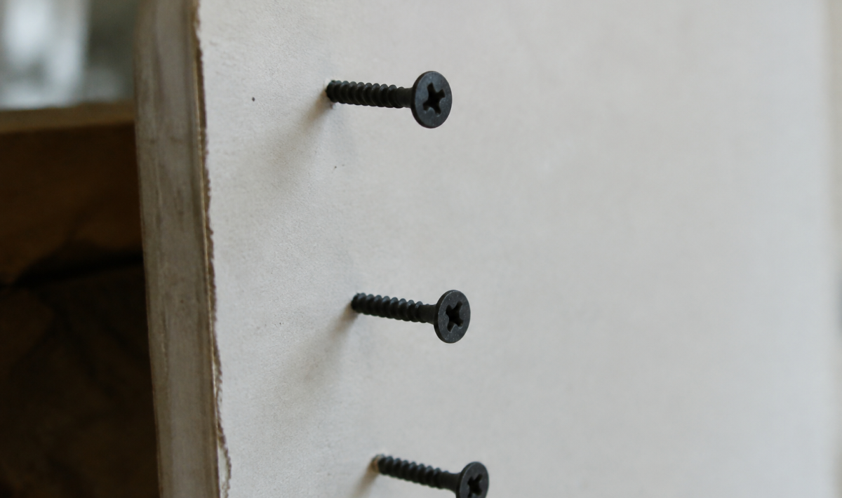 Vis noires plantees dans une plaque de platre blanche